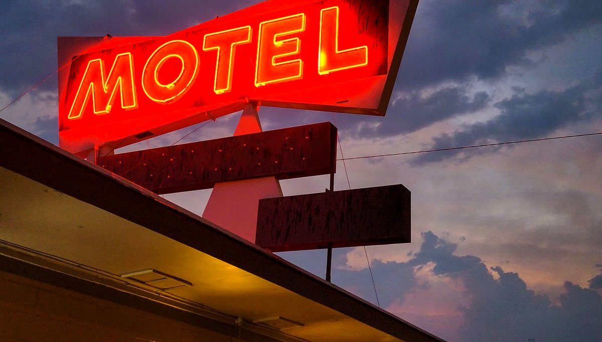 A red neon motel sign against the dark
